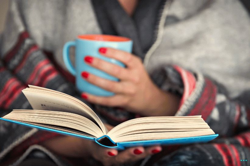 एक किताब पढ़ने वाली एक कंबल से लिपटी महिला की स्टॉक फोटो।